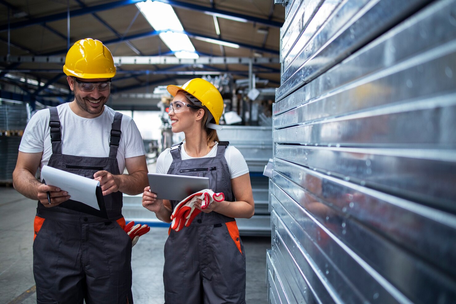 Obreros de fábrica recorriendo una planta industrial discutiendo sobre la eficiencia de la producción